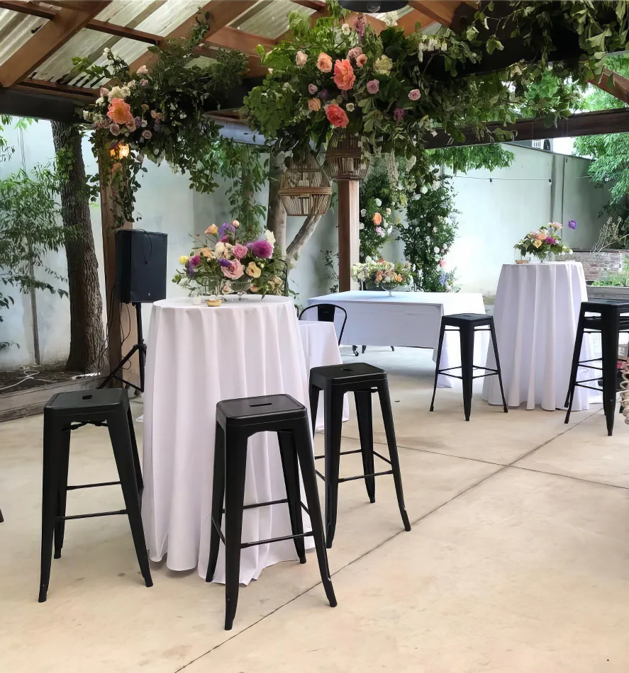 A table set up with black Tolix stools and flowers.