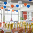 A room filled with orange Tolix stools and colorful balloons.