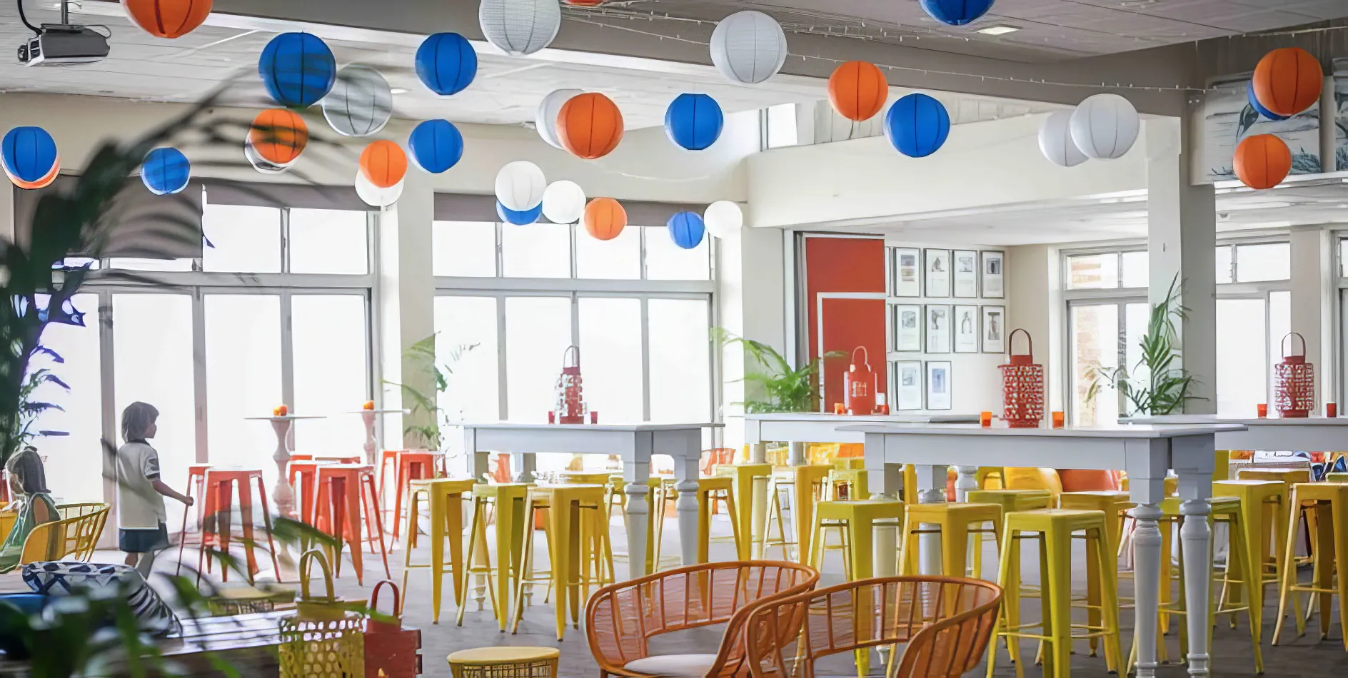 A room filled with orange Tolix stools and colorful balloons.