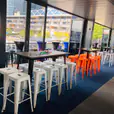 A room with orange Tolix stools and tables scattered throughout, creating a vibrant and inviting bar atmosphere.