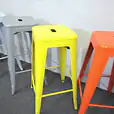 A row of vibrant yellow Tolix stools.