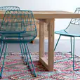 A dining table with turquoise blue chairs and a rug.