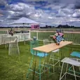 A turquoise wire stool is set up on a grassy field.