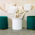 Two green velvet ottoman stools on display