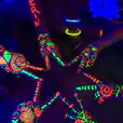 A group of people with glow in the dark paint on their hands illuminated by UV black light.