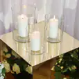Three vases with candles on top of a gold plinth.