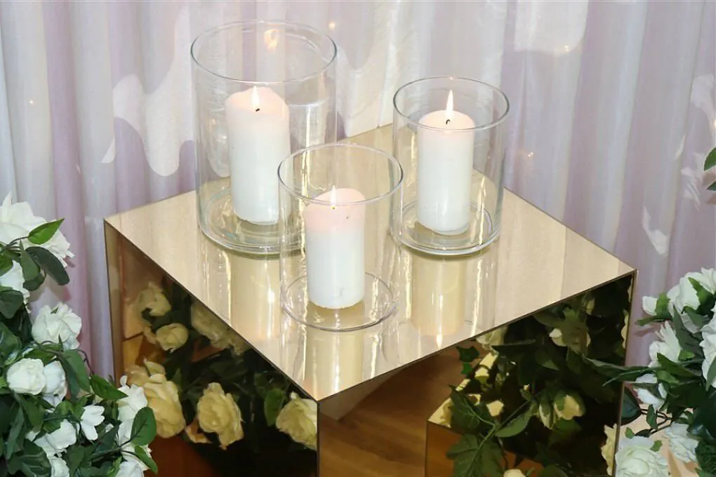 Three vases with candles on top of a gold plinth.