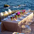 A table set up on a cliff overlooking the ocean, enhanced with Victorian Ghost Chair Hire.