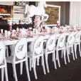 A table set up with white Victorian chairs and a white tablecloth.
