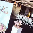 A wedding reception set up with white Victorian chairs and pink flowers.