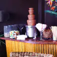 A table with a chocolate fountain, vase of flowers, and wafer biscuits (per 100 biscuits).