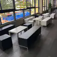 A group of black and white benches arranged in a room with large windows.