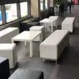 A group of white couches and rectangular tables in a lobby.