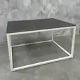 White Rectangular Coffee Table Hire w/ Black Top next to a marble wall
