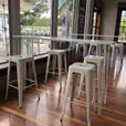 In a trendy restaurant, elegant white stools gently punctuate the warm wooden floor.