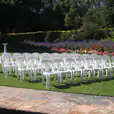 A row of white plastic chairs in a garden.