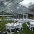 A large tent set up for a wedding reception, illuminated with white rice lanterns.
