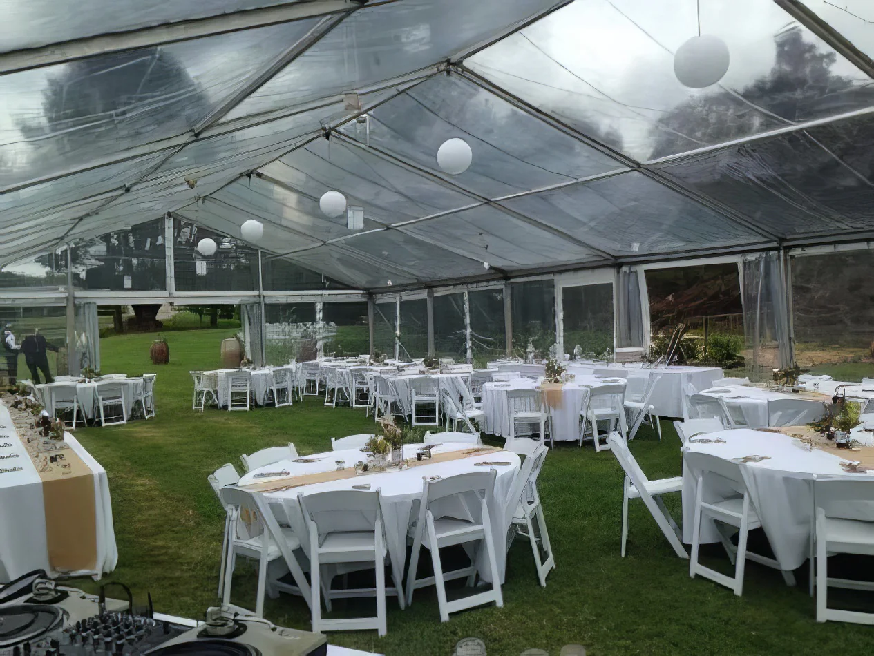 A large tent set up for a wedding reception, illuminated with white rice lanterns.