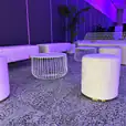 A white wire table next to a lounge setting in beautiful purple light