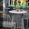 A group of tables and chairs in an outdoor area, including White Arrow Stool Hire.