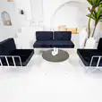 A White cross coffee table next to a blue lounge