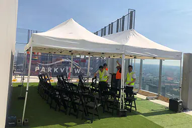 White rooftop event canopies set up with black seating, artificial grass flooring, glass balustrades and city views for a corporate function