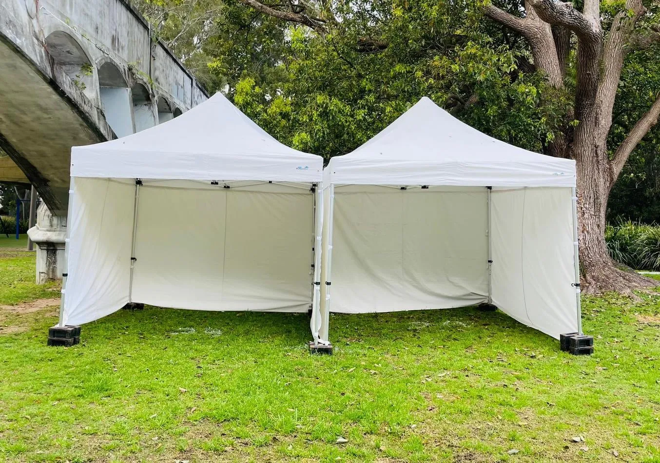 Two 3mx3m Pop Up Marquees with Walls on a grassy area.