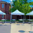 Four 3mx3m Pop Up Marquees with White Roofs set up in front of a brick building.