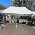 A white 3mx6m pop-up marquee with chairs set up in front of a building.