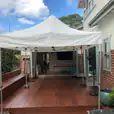 A 3mx6m pop up marquee with a white roof set up on a wooden deck.