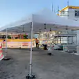 A 4mx8m Pop Up Marquee with a white roof is being set up in front of a building.