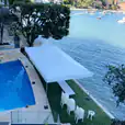 A house with a swimming pool and a 4mx8m Pop Up Marquee w/ White Roof next to the water.