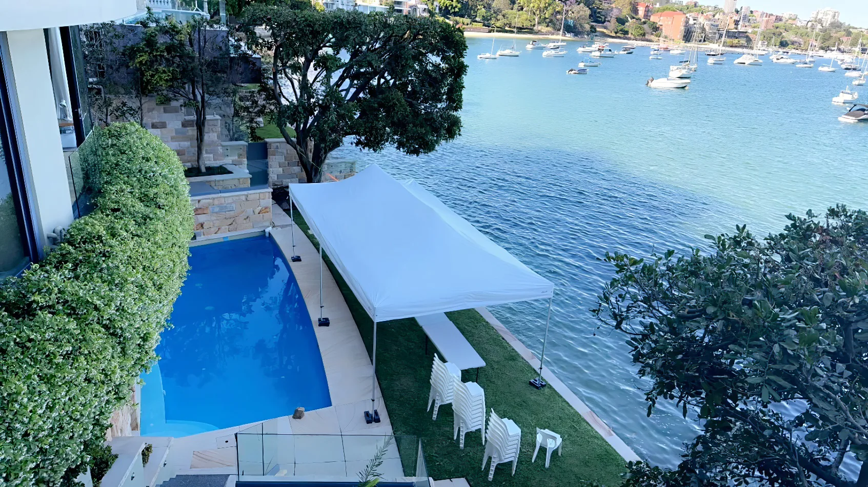 A house with a swimming pool and a 4mx8m Pop Up Marquee w/ White Roof next to the water.