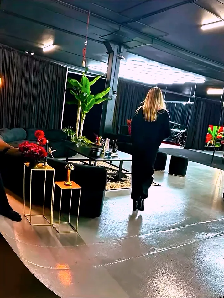 Black velvet ottoman stools used as loose seating in an industrial event space with black draping.