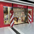 Red and white spiral balloon pillars placed on either side of a toy store entrance in a shopping centre, adding a festive decorative display suitable for retail promotions or event theming.