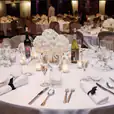 A round black and white table setting with white linens and silverware.