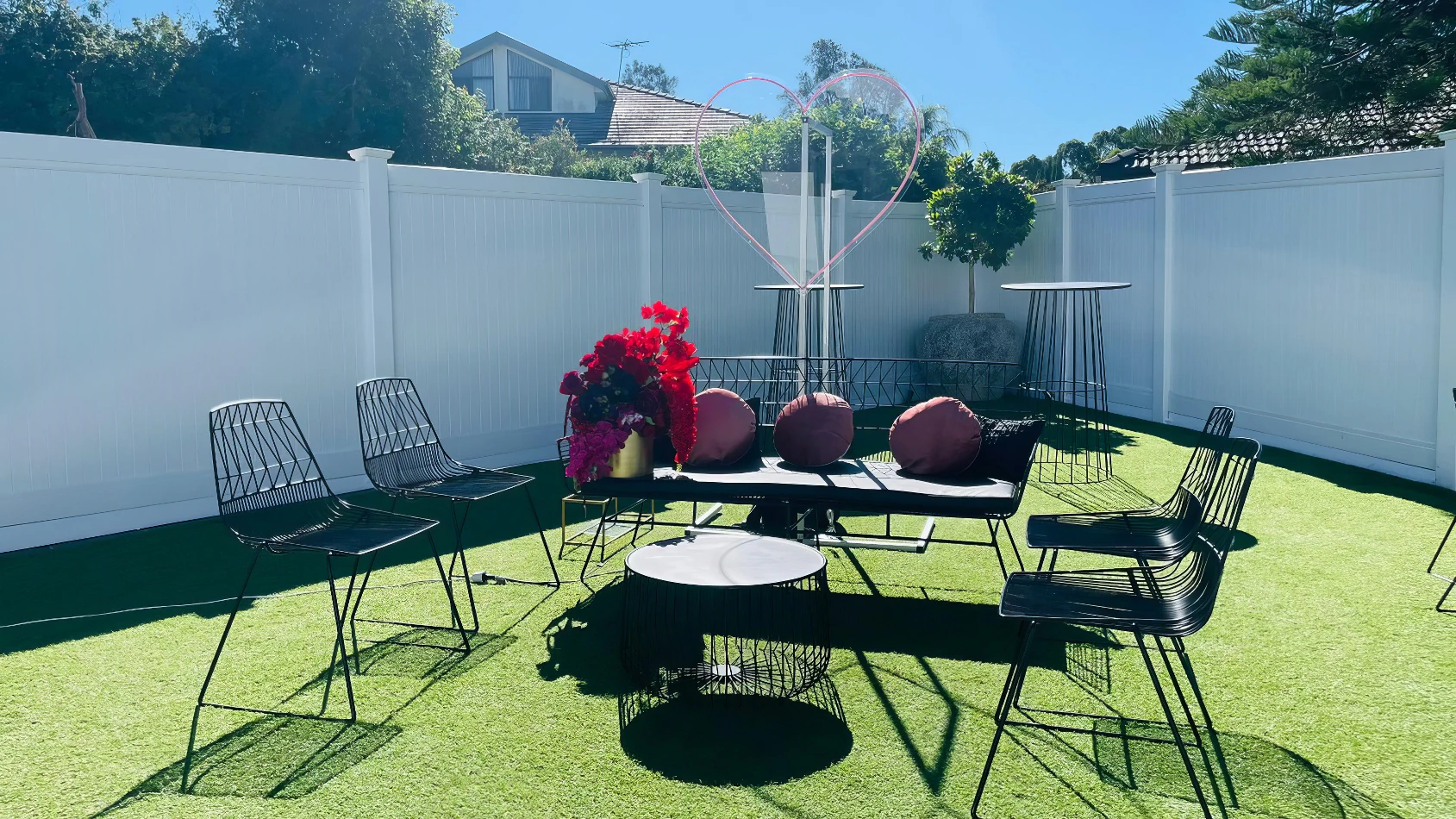 A backyard with black wire furniture and white fence featuring the Black Arrow 3 Seater Sofa.