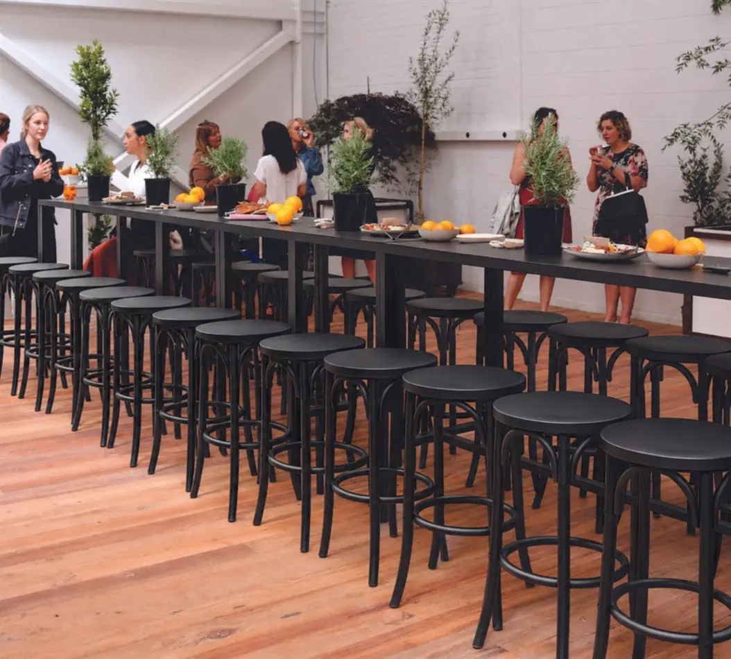 Multiple black bentwood bar stools arranged at a high bar table for a corporate cocktail function