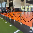 Black velvet bollard ropes and chrome stanchions arranged as crowd barriers around an indoor sports event training area