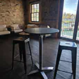 Black cocktail table with industrial black bar stools positioned inside a harbour-side function venue with exposed brick walls