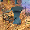 Black cocktail table with fitted black lycra cover surrounded by modern black wire bar stools in an event venue