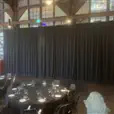 Black event draping used behind round dining tables in a large indoor function space