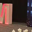 Black draping along a corporate event room with cocktail tables, lounge furniture, display signage and red accent lighting