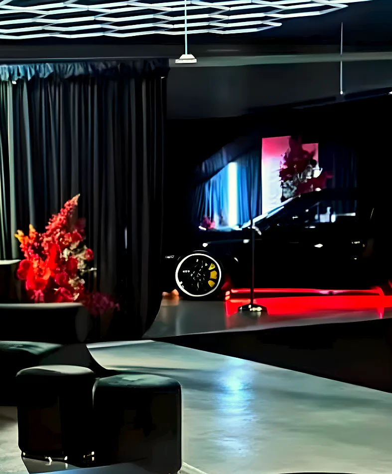 Black velvet ottoman stools set out against black draping at a supercar showroom event.