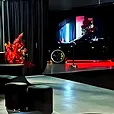 Black velvet ottoman stools set out against black draping at a supercar showroom event.