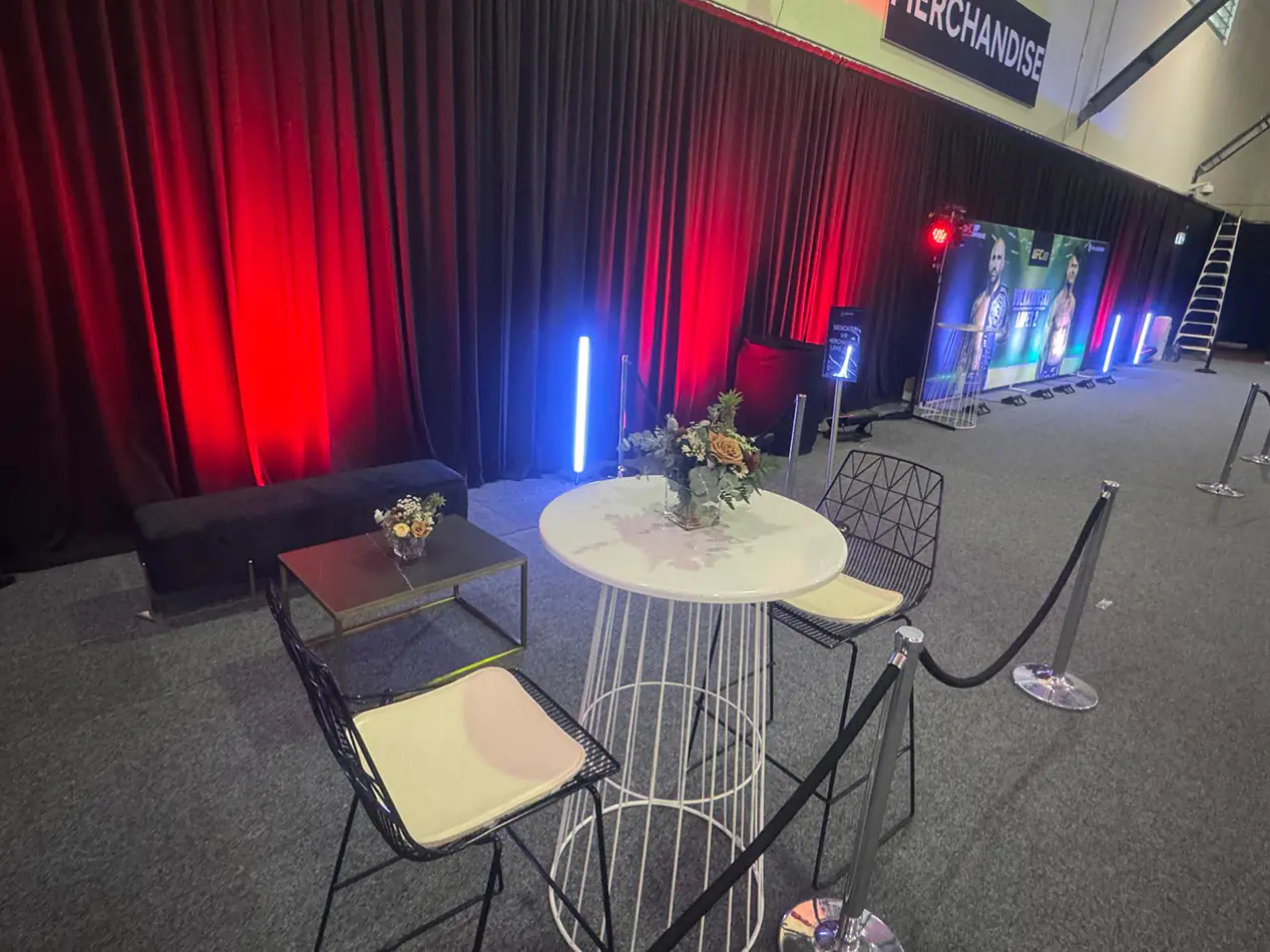 Black event draping with red uplighting behind a lounge and cocktail seating area in an indoor event venue