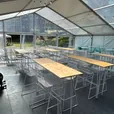 Black hairpin bar tables and stools under festoon lights at an event