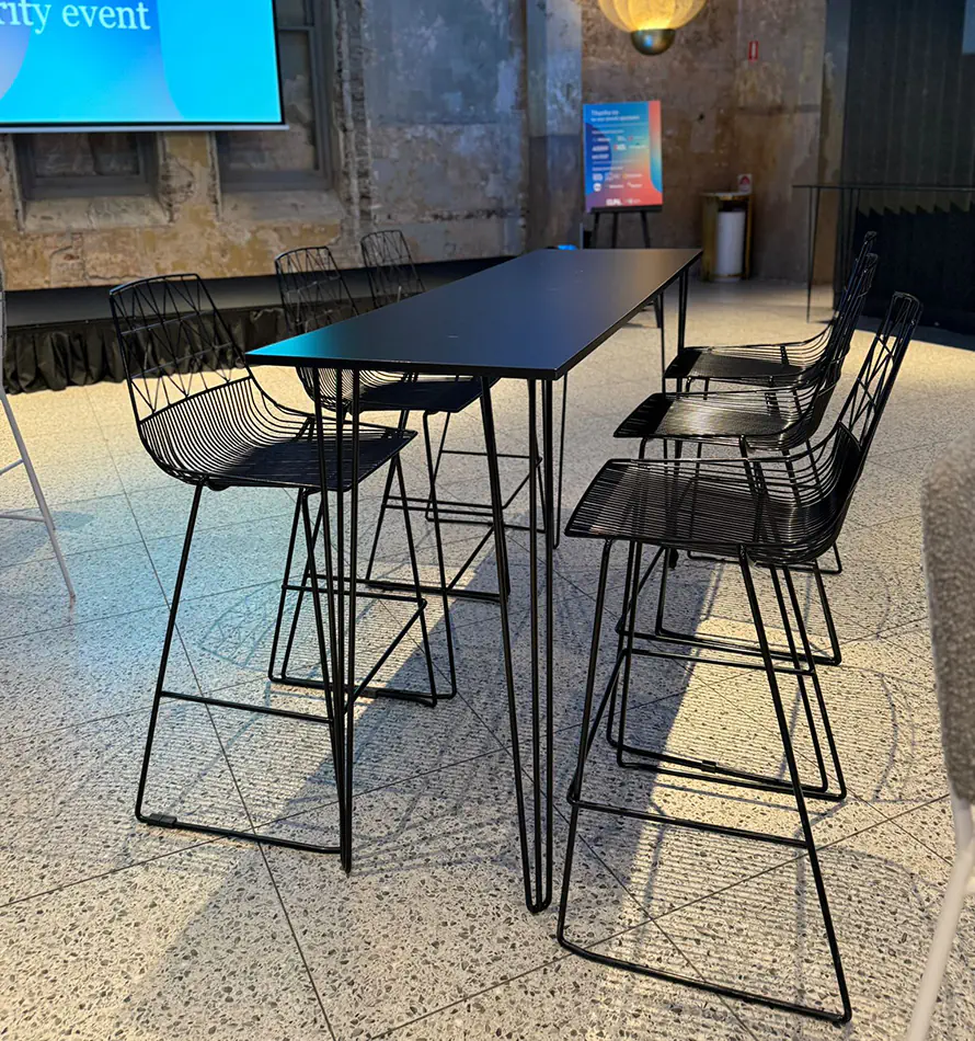 Black hairpin bar table paired with black wire bar stools in a stylish contemporary event venue with industrial finishes