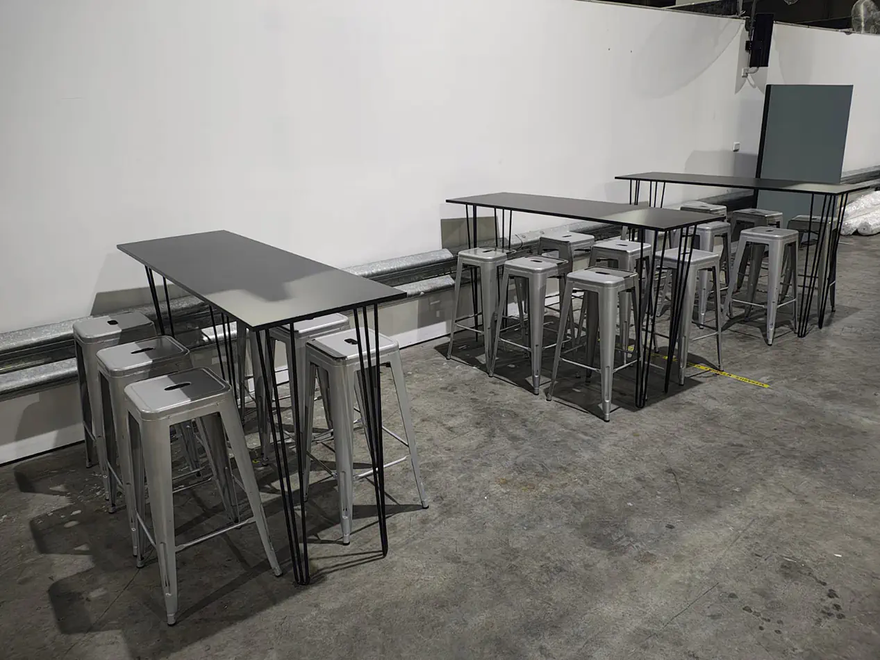 Black hairpin bar tables paired with silver industrial stools arranged in a warehouse event furniture setup