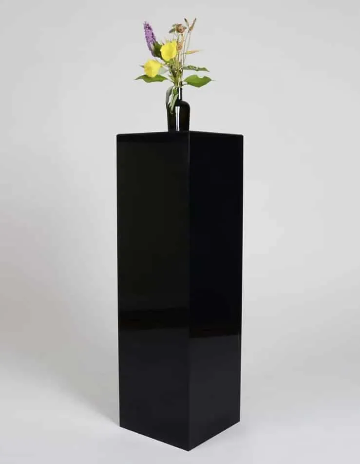 A large black vase stands on top of a square plinth.